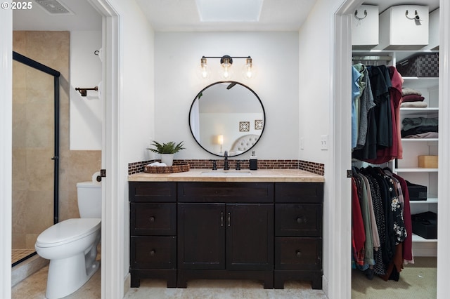 bathroom featuring a shower with door, vanity, and toilet