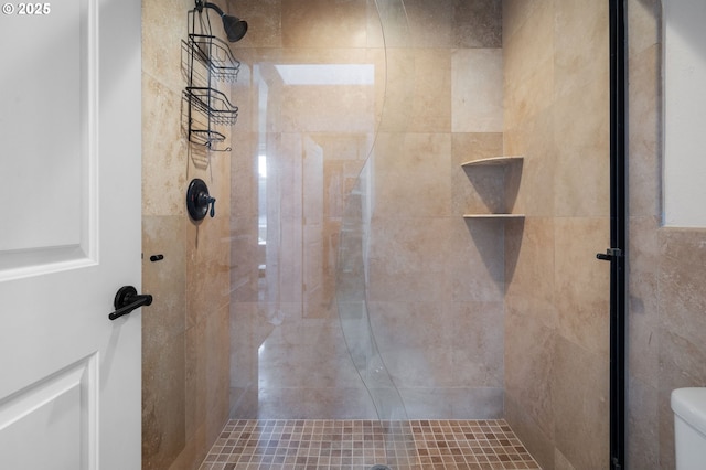 bathroom with a tile shower and toilet