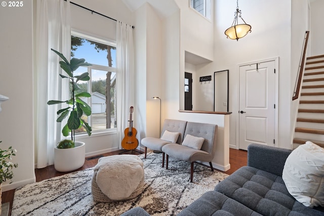 living room featuring a towering ceiling, a healthy amount of sunlight, and dark hardwood / wood-style flooring