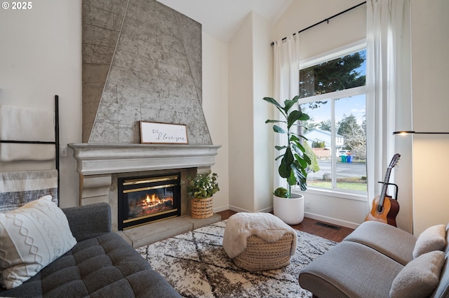 sitting room featuring vaulted ceiling, hardwood / wood-style floors, and a fireplace