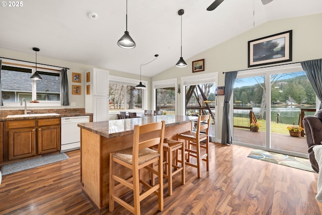 kitchen featuring white dishwasher, wood finished floors, a sink, vaulted ceiling, and brown cabinets