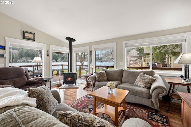 living room with lofted ceiling, a wood stove, wood finished floors, and a wealth of natural light