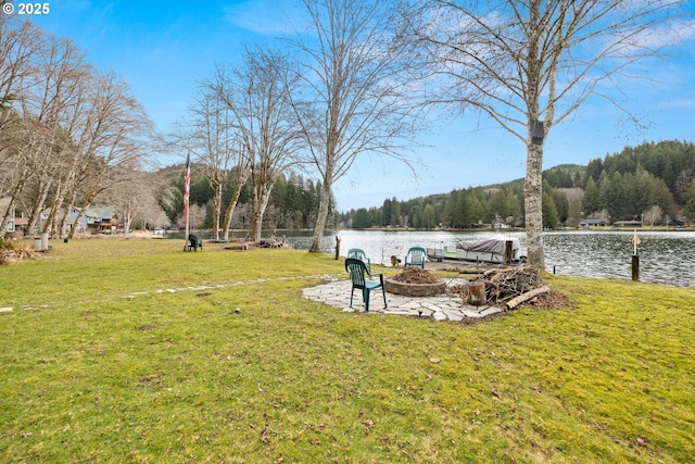 view of property's community with a fire pit, a lawn, and a water view