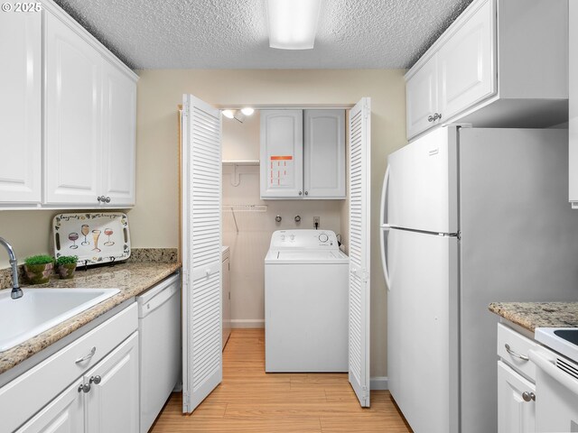 7116 SW Murray Blvd, Beaverton, OR 97008 - kitchen featuring washer / clothes dryer, white appliances, light wood-type flooring, a textured ceiling, and white cabinets