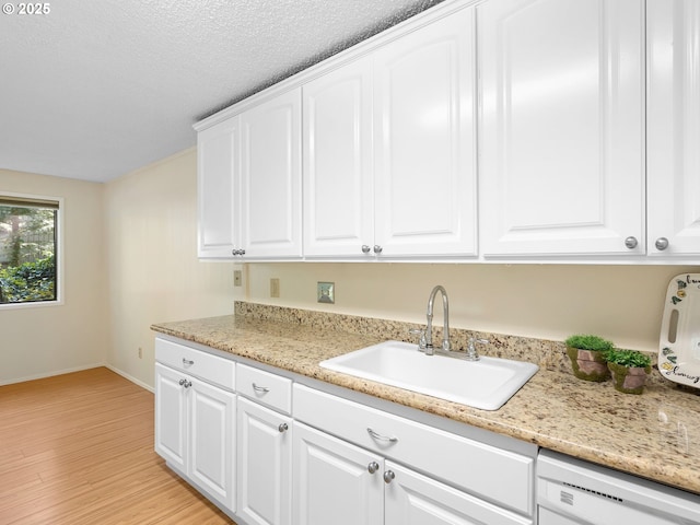 7116 SW Murray Blvd, Beaverton, OR 97008 - kitchen with white dishwasher, a sink, light wood-type flooring, baseboards, and white cabinetry
