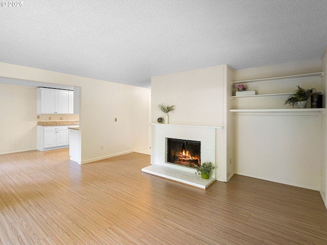 7116 SW Murray Blvd, Beaverton, OR 97008 - unfurnished living room featuring a fireplace, light wood-style flooring, a textured ceiling, and baseboards