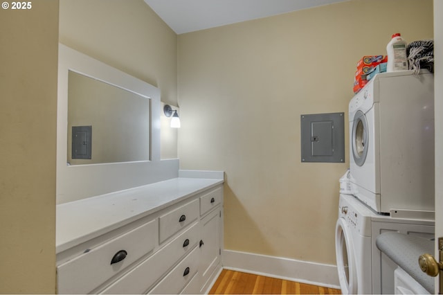 washroom with electric panel, light wood-style flooring, baseboards, and stacked washer and dryer
