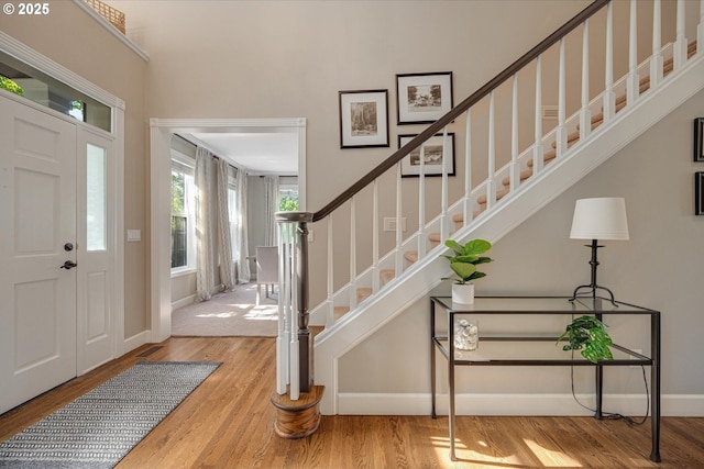 entryway featuring wood finished floors, stairs, and baseboards