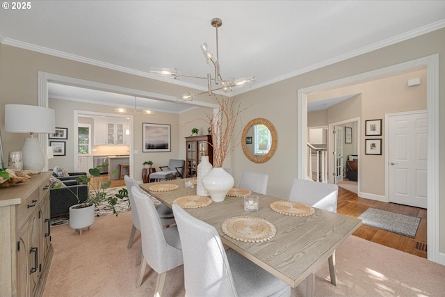 dining area with a chandelier, crown molding, light wood finished floors, and baseboards