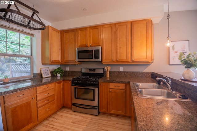 9235 NW Germantown Rd, Portland, OR 97231 - kitchen with stainless steel appliances, a peninsula, brown cabinetry, light wood finished floors, and pendant lighting