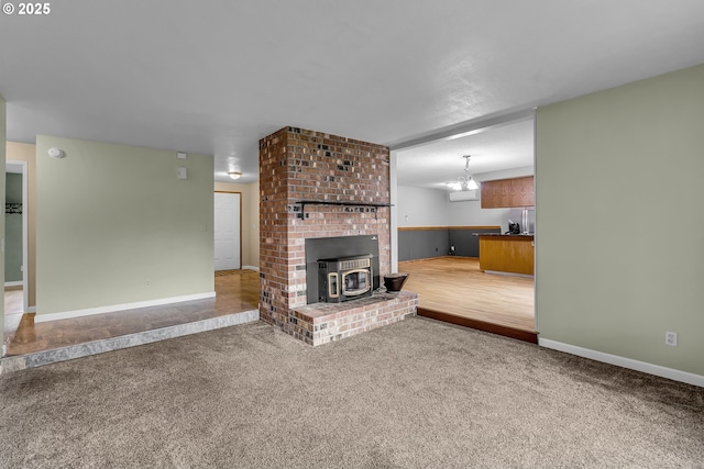 unfurnished living room featuring a wood stove, baseboards, and carpet floors