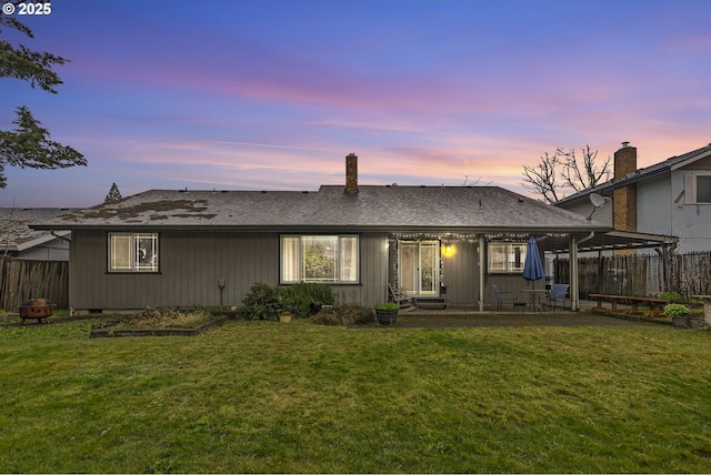 back of house with a fire pit, a yard, fence private yard, and a shingled roof