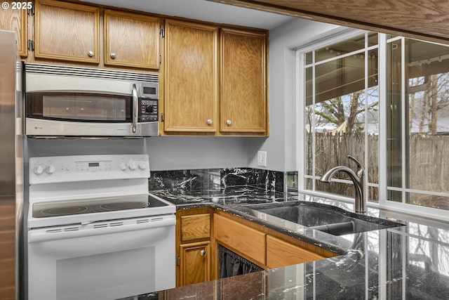 kitchen with dark stone counters, white electric range oven, a sink, brown cabinetry, and stainless steel microwave