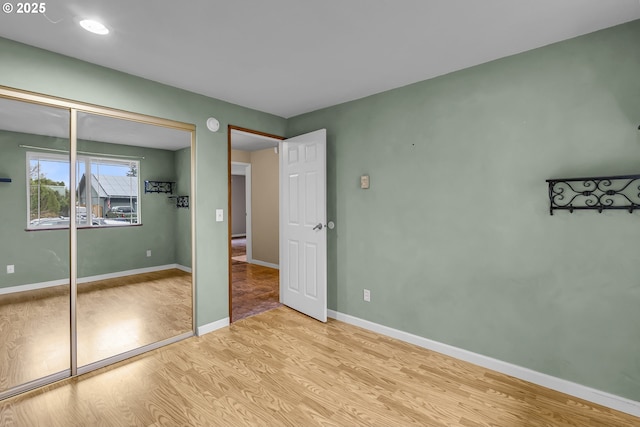 unfurnished bedroom with light wood-style flooring, baseboards, and a closet