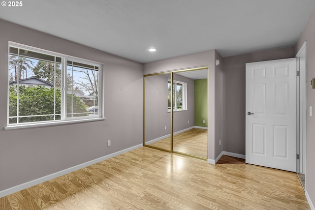 unfurnished bedroom with recessed lighting, light wood-style flooring, a closet, and baseboards