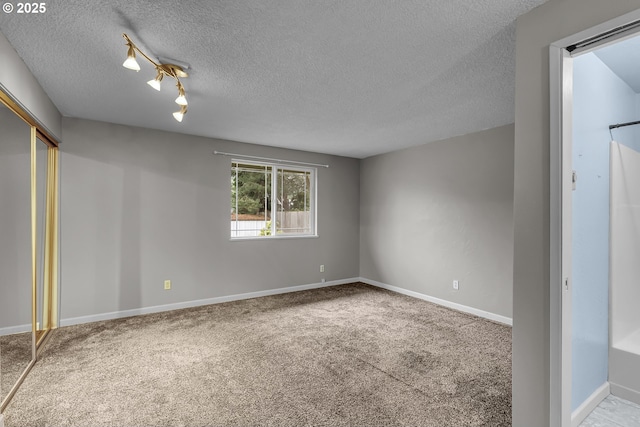 unfurnished bedroom with carpet, baseboards, a closet, and a textured ceiling