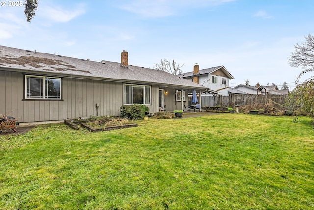 back of property with a lawn, fence, a patio, and a vegetable garden
