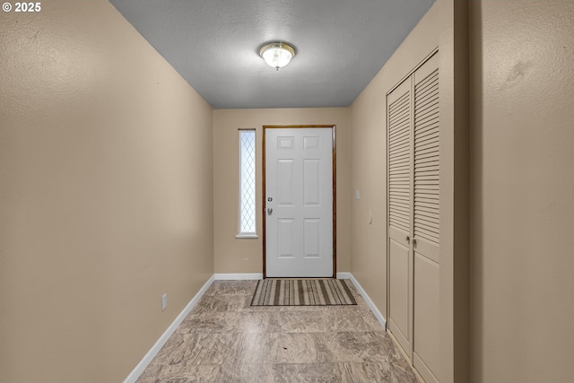 foyer with a textured ceiling and baseboards