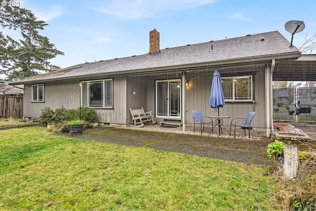 rear view of property featuring a shingled roof, fence, a lawn, a chimney, and a patio