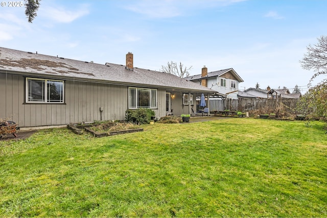 back of property featuring board and batten siding, fence, a patio, a yard, and a vegetable garden