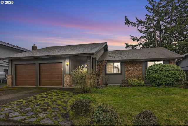 view of front of property featuring a lawn, a garage, and driveway