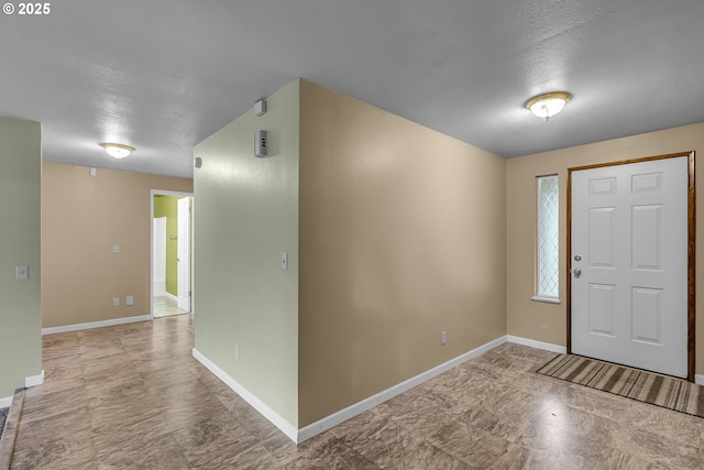 foyer entrance with baseboards and a textured ceiling