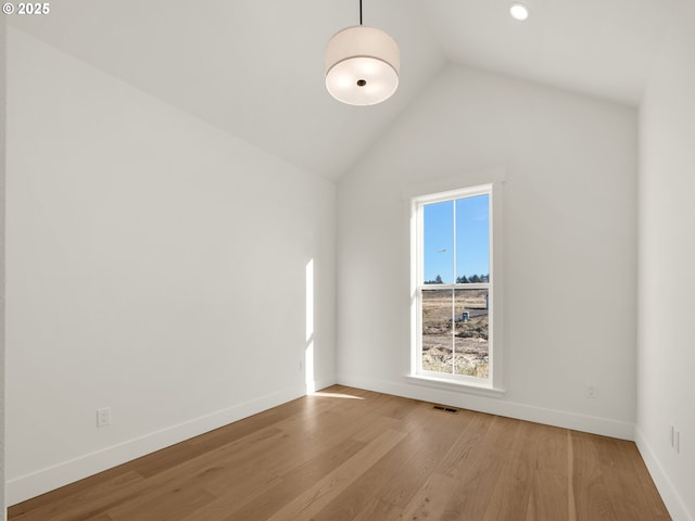 spare room featuring lofted ceiling and light hardwood / wood-style floors