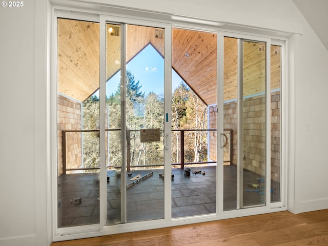 doorway with floor to ceiling windows, lofted ceiling, and hardwood / wood-style floors