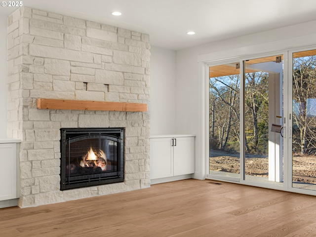 unfurnished living room with a stone fireplace and light hardwood / wood-style flooring