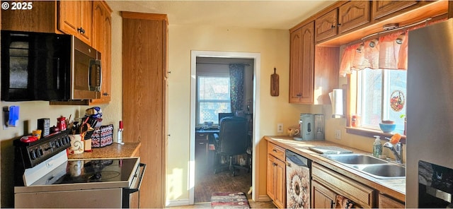 kitchen with a sink, stainless steel appliances, brown cabinets, and light countertops