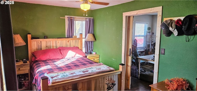 bedroom with multiple windows, a ceiling fan, and a textured wall