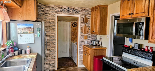 kitchen featuring stainless steel microwave, electric stove, brown cabinetry, and a sink