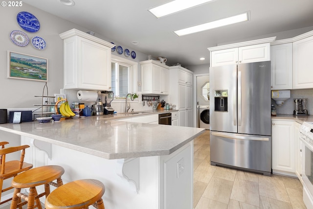 161 Single Pine Ln, Winchester, OR 97495 - kitchen featuring stainless steel fridge with ice dispenser, estacked washer and dryer, a peninsula, white cabinets, and recessed lighting