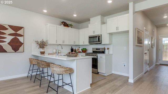 6558 SE Nasha St, Hillsboro, OR 97123 - kitchen featuring appliances with stainless steel finishes, light wood-style floors, a kitchen breakfast bar, a peninsula, and recessed lighting