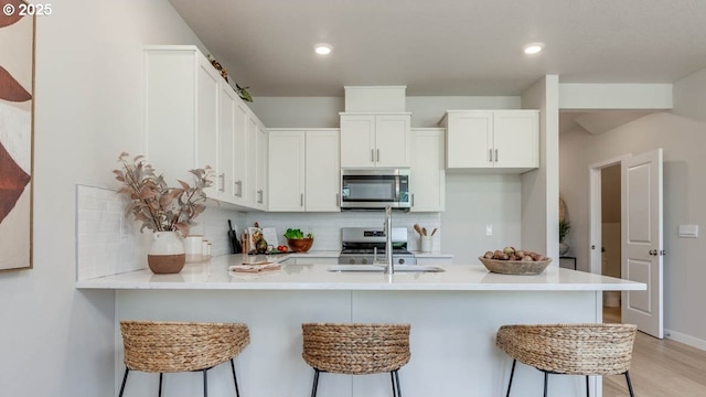 6558 SE Nasha St, Hillsboro, OR 97123 - kitchen featuring appliances with stainless steel finishes, tasteful backsplash, a peninsula, a kitchen breakfast bar, and light countertops