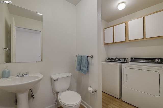 7197 SW Sagert St Unit 103, Tualatin, OR 97062 - half bathroom featuring separate washer and dryer, toilet, wood finished floors, baseboards, and a sink