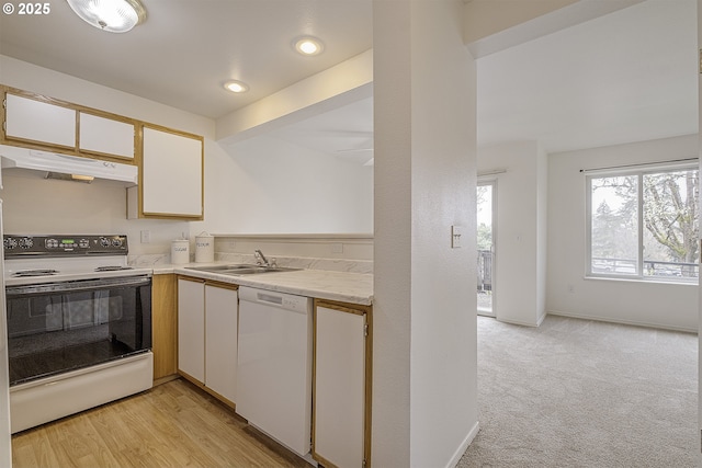 7197 SW Sagert St Unit 103, Tualatin, OR 97062 - kitchen with white appliances, a sink, under cabinet range hood, white cabinets, and light colored carpet