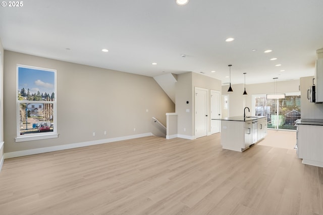 kitchen featuring recessed lighting, a kitchen island with sink, white cabinetry, and light wood-style floors