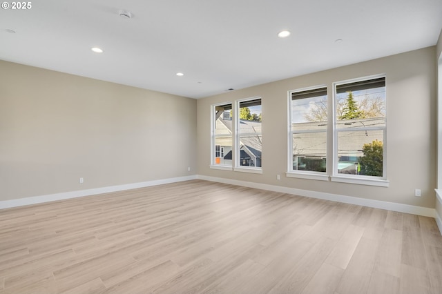 spare room featuring light wood-type flooring, recessed lighting, and baseboards
