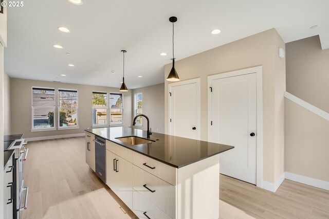 kitchen featuring a sink, light wood-type flooring, dark countertops, baseboards, and stainless steel dishwasher