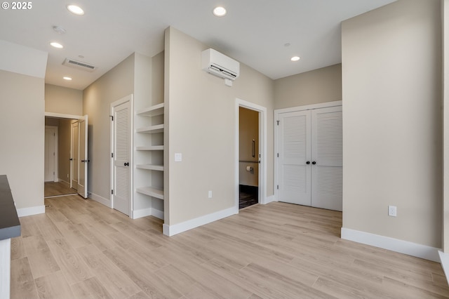 unfurnished room featuring a wall mounted AC, baseboards, recessed lighting, and light wood finished floors
