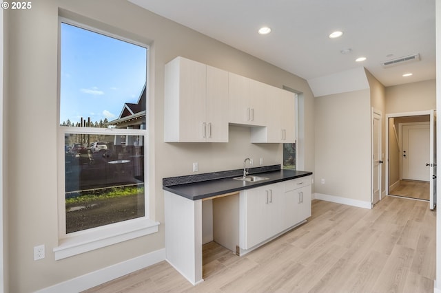 kitchen featuring a sink, dark countertops, light wood-type flooring, baseboards, and recessed lighting