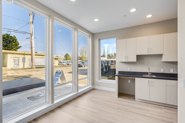 kitchen with a sink, dark countertops, light wood-style floors, recessed lighting, and baseboards