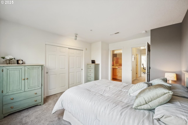 carpeted bedroom featuring ensuite bathroom and a closet