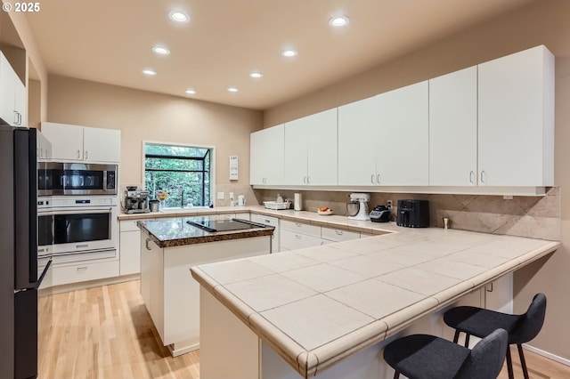 9220 SW 175th Ave, Beaverton, OR 97007 - kitchen featuring a peninsula, black appliances, recessed lighting, and light wood-style flooring