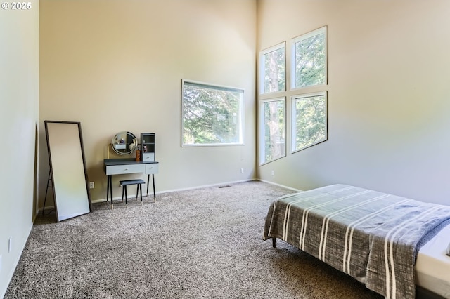 bedroom with carpet floors, a high ceiling, and baseboards