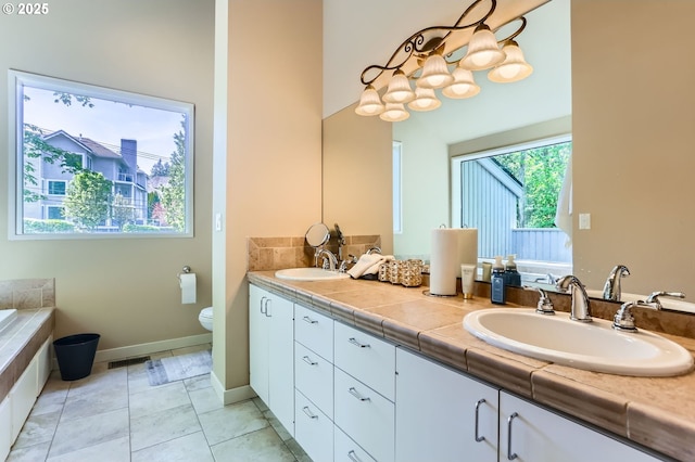 full bathroom featuring double vanity, a sink, baseboards, and toilet