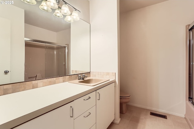 full bath featuring vanity, toilet, baseboards, a shower with door, and visible vents