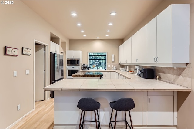 kitchen featuring stainless steel appliances, recessed lighting, tasteful backsplash, and a peninsula
