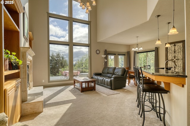 living room with light colored carpet, a high ceiling, and a chandelier